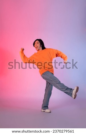 Image of a young Asian person dancing on a neon colored background