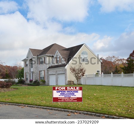 Real Estate for sale open house welcome sign Suburban brick McMansion style home with two car garage white picket fence residential neighborhood blue sky clouds USA