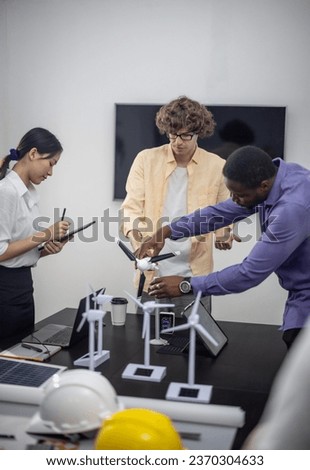 A diverse startup team develop, collaborates on a powerful, lightweight, portable wind turbine prototype, aligning with potential user demand and renewable energy needs to secure investor funding. Royalty-Free Stock Photo #2370304633