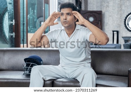 Indian man in cricket dress watching Cricket at home sitting on sofa , Cricket concept