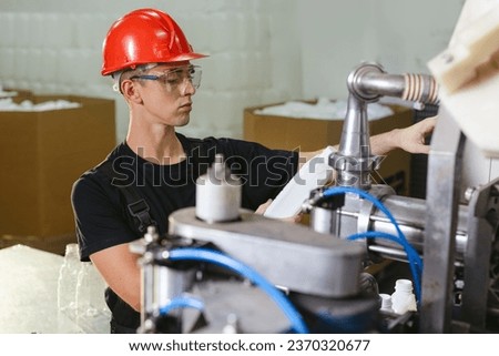 Production line worker or technologist in uniform working in chemical industry and checking quality of liquid soap. Royalty-Free Stock Photo #2370320677