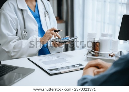 Healthcare costs and fees concept.Hand of smart doctor used a calculator and smartphone, tablet for medical costs at hospital in morning light
