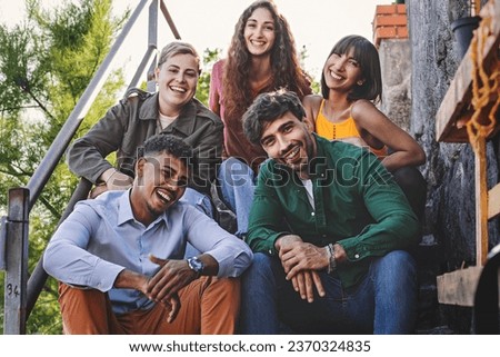 Diverse Friends Posing on Staircase - A group of five diverse friends posing on a staircase at sunset in a tourist location, smiling, looking at the camera, and enjoying their time together. Royalty-Free Stock Photo #2370324835