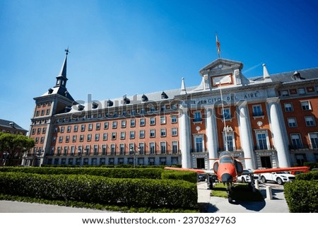 Airplane in front of Spanish flag on General Headquarters building of the Air Space Force on calle de la Princesa street Royalty-Free Stock Photo #2370329763