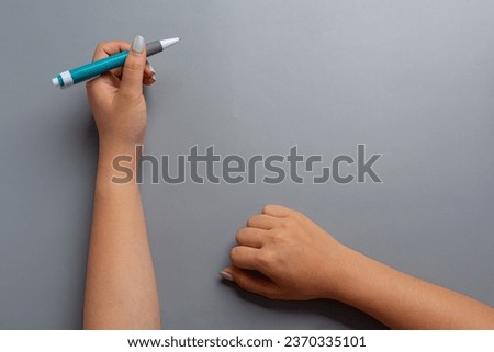 a woman left-hand with a pen.Left hander day concept.  Royalty-Free Stock Photo #2370335101