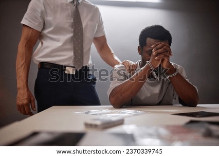 Portrait of young Black man crying in interrogation room at police department