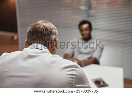 Back view of white haired detective interrogating criminal suspect in police department, copy space