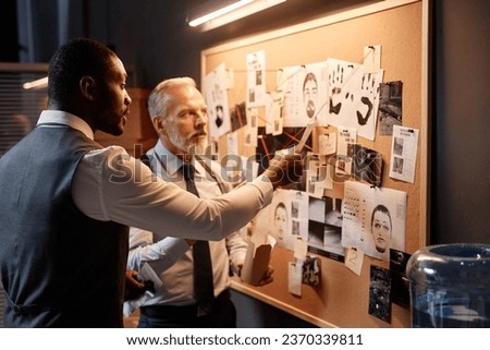 Side view portrait of African American detective pointing at evidence board while investigating case