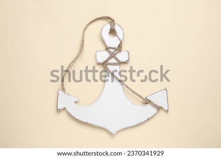 White anchor with hemp rope on beige background, top view