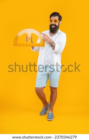 photo of man hold geometry protractor, pointing finger isolated on yellow