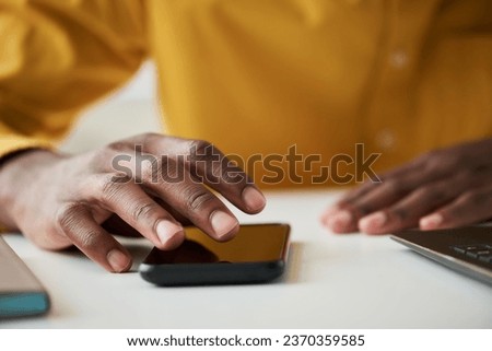 Focus on fingers of right hand of young male office worker over smartphone screen scrolling through contacts while sitting by desk