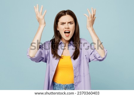 Young displeased sad woman she wears purple shirt yellow t-shirt casual clothes spread hands cream shout look camera isolated on plain pastel light blue background studio portrait. Lifestyle concept Royalty-Free Stock Photo #2370360403
