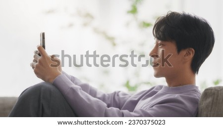 South Korean Young Man Enjoying His Leisure Time while Relaxing and Using a Smartphone. Asian Male Using Productivity Apps, Social Media Network and Personal Development Tools Royalty-Free Stock Photo #2370375023