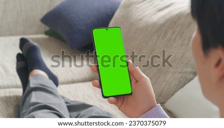 Over the Shoulder Footage of an Anonymous Male Relaxing at Home, Using Smartphone with Green Screen Mock Up Display to Seamlessly Manage Tasks and Projects from a Remote Work Location