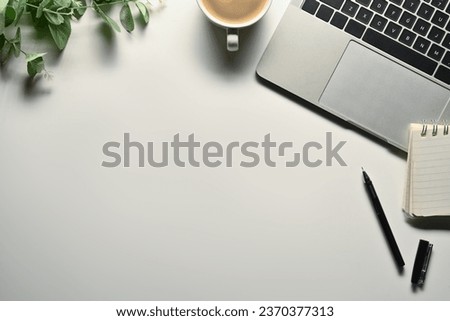 White office desk with laptop, cup of coffee, notepad and plant. Top view with space for text.
