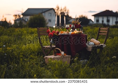 Elegant beautiful dinner table setting for thanksgiving or wedding celebration outdoors, fall countryside style, pumpkin as decor. Romantic atmosphere of a date, sunset. Cheese board, red wine Royalty-Free Stock Photo #2370381431