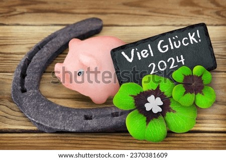Lucky symbols marzipan piggy and clover with German Good Luck 2024 on wooden background Royalty-Free Stock Photo #2370381609