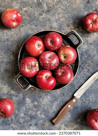 Eco Apples on retro grill plate on black concrete background with knife. Food photo with autumn eco friendly Fruits in rustic style. Top view on Organic apple on the table.
