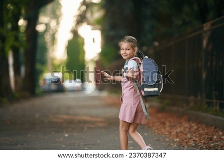 Schoolgirl with backpack is outdoors.