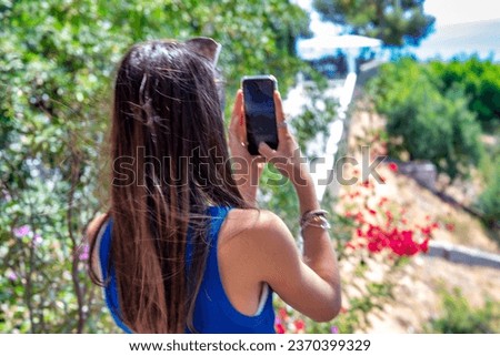 A happy young girl taking pictures of beautiful countryside.
