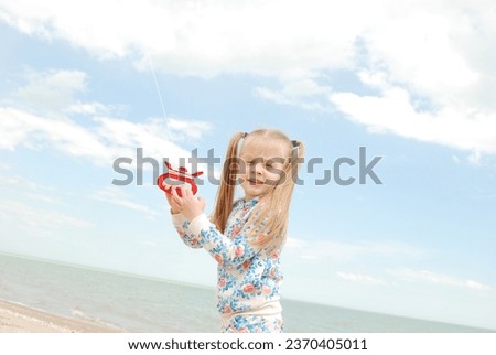 a little girl flies a kite on the beach on a sunny day. Children's joy. Day with family