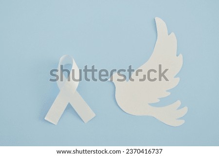 White ribbon as a symbol of peace and a paper bird on blue. Forgiveness Day