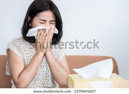 Asian woman sneezing because of cold and flu, dust allergy  Royalty-Free Stock Photo #2370441607