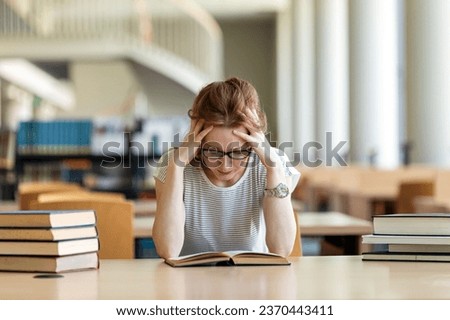 Exhausted young female studying and preparing for exam in college library. Education people concept