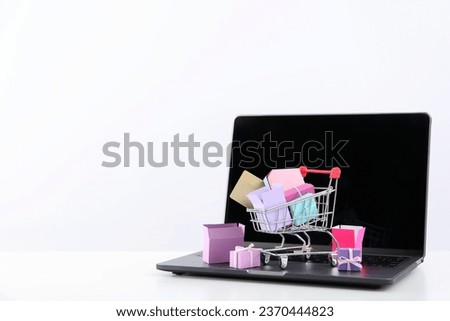 Shopping cart with packages, thumbnail on laptop.