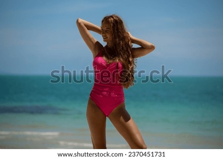 Beautiful young woman in pink swimsuit posing on the beach. High quality photo