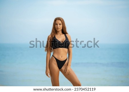 Beautiful young woman in black bikini on the beach at sunset. High quality photo