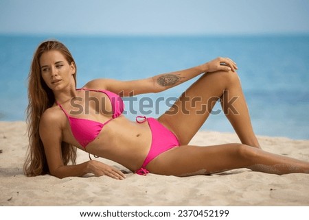 Beautiful young woman in pink bikini sunbathing on the beach. High quality photo