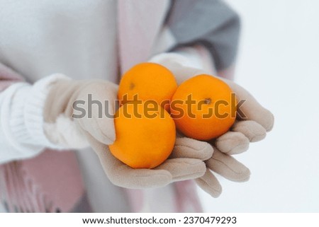 Woman with tangerines in hands in winter forest, christmas or new year holidays concept. Close up