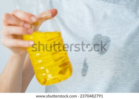 Grease stains in a clothes. An unrecognized woman is holding a corn oil. daily life stain concept. High quality photo Royalty-Free Stock Photo #2370482791