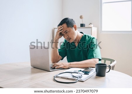 Adult Asian male doctor feeling confused and headache while looking at laptop screen at clinic. Medical student having problem during test. 