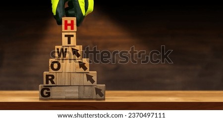 Gloved hand arranging wood blocks with text Growth and arrows symbol, above a wooden table or desk with copy space.