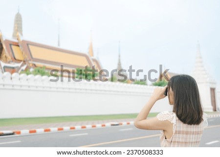 Unknown young woman standing and taking a photo with camera. Woman travel at Wat Pra Kaew Temple in Bangkok.