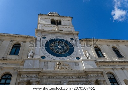 Astronomical clock tower in a square in the historic center of Padua, against the blue sky.