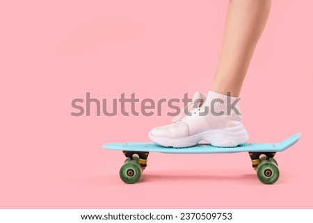 Young woman with skateboard on pink background, closeup