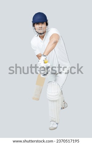 Portrait of young man in cricket dress with helmet playing cricketing shot ,Young man Playing cricket indoor concept shoot