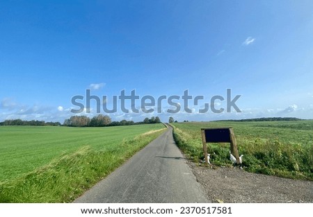 Countryside view at Denmark countryside with the road, farm, blue sky and Plank of black sign board at the side