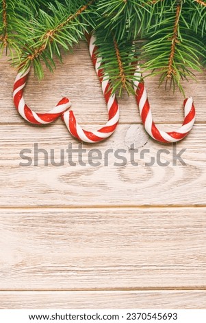 Christmas tree branch and candy cane on a wooden table or board for background. New year theme. Space for text. Toned.