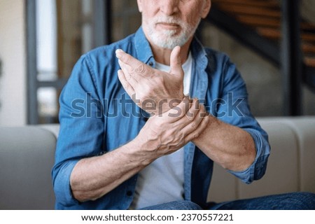 Cropped shot of unhappy middle aged man suffering from wrist pain, feeling numb and discomfort in hand. Elderly male has joint ache and inflammation. Arthritis treatment concept