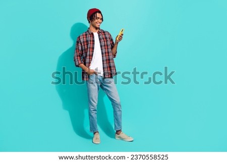 Full size portrait of cheerful cool person use smart phone chatting empty space advert isolated on turquoise color background