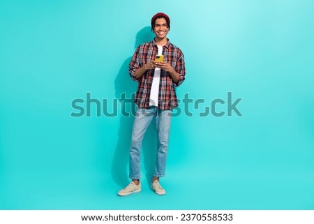 Full size photo of positive young man hold use smart phone texting typing blog post isolated on aquamarine color background