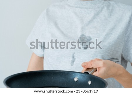 Close up grease stains in a gray clothes. An unrecognized woman is holding a frying pan with oil. daily life stain concept. High quality photo Royalty-Free Stock Photo #2370561919