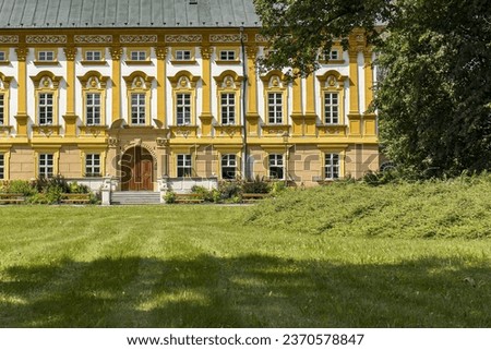 Abstract photograph of the castle building captured from the park. Castle park with trees and grass. Part of the yellow castle building. Castle, park, travel, summer, monuments