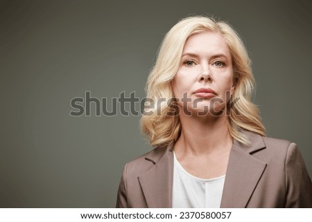 Portrait of a beautiful well-groomed middle-aged business woman on a gray studio background. Women's beauty. Successful lifestyle. Place for text. Royalty-Free Stock Photo #2370580057