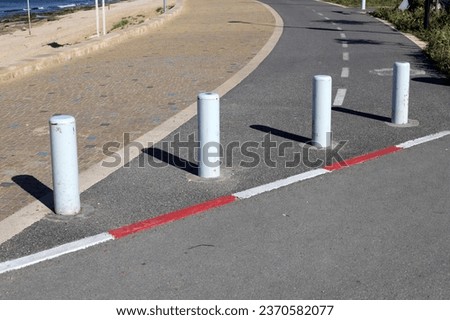 A row of pillars along the road for the safe passage of pedestrians along the sidewalk.