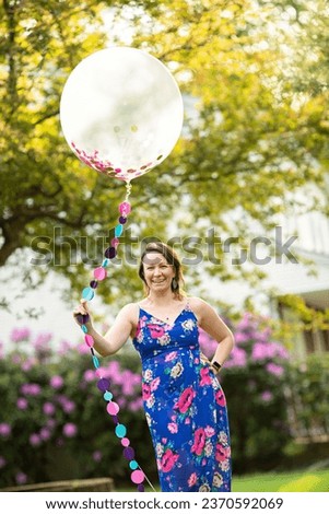 Vertical image of a woman smiling and holding a big balloon